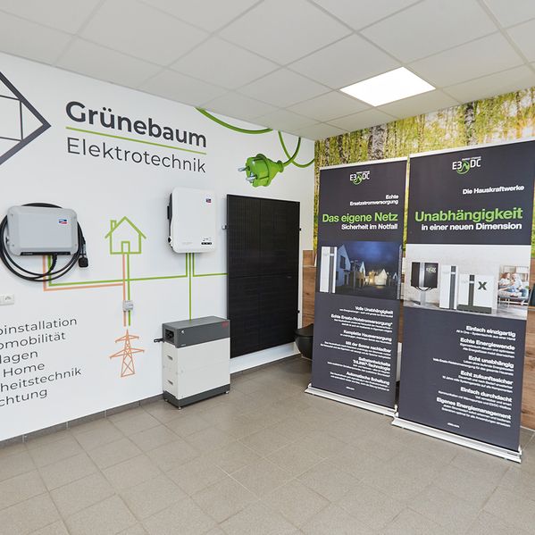 Innenraum eines Technik-Showrooms mit Energielösungen, darunter Sonnenkollektoren, Batterien und Informationsbanner zu Unabhängigkeit und Sicherheit.