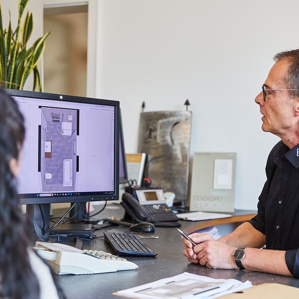 Ein Mann, der eine Planung des Badezimmers am PC zeigt.