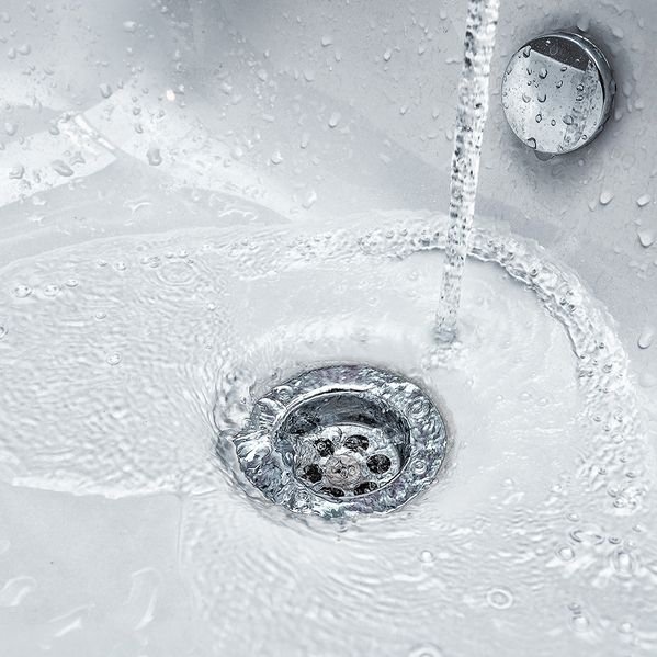 Ein Waschbecken aus der Nähe, in das Wasser hineinfließt.