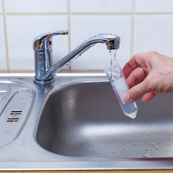 Eine Person, die eine Probe vom Leistungswasser nimmt.