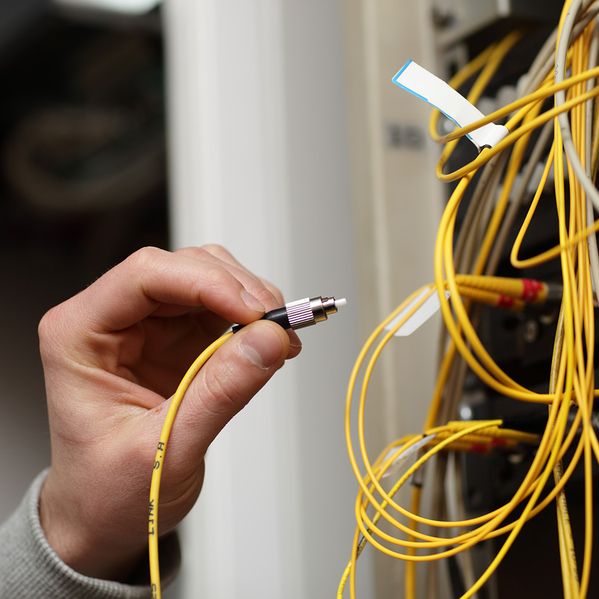 Eine Person, die ein Kabel in einen Stromkasten steckt.