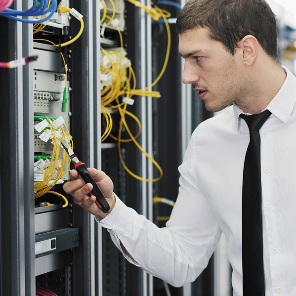 Eine Person mit Werkzeug, die an einem Stromkasten steht.