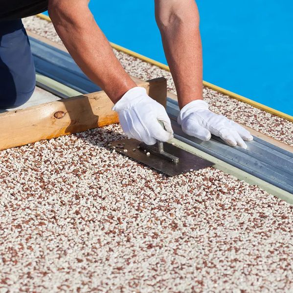 Rot-weißer Natursteinteppich wird vom Fachmann verlegt