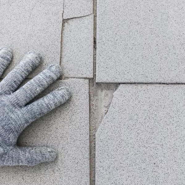 Eine Hand neben kaputten Fliesen